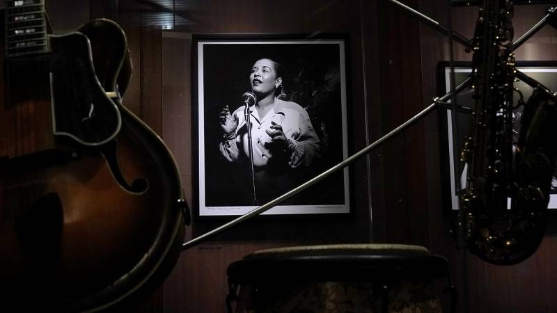 A portrait of Billie Holiday hanging on the wall surrounded by instruments