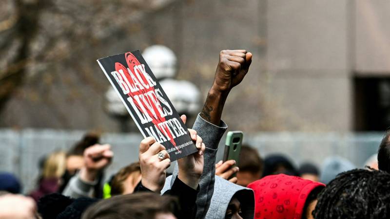 A fist in the air next to a sign that reads "Black Lives Matter"