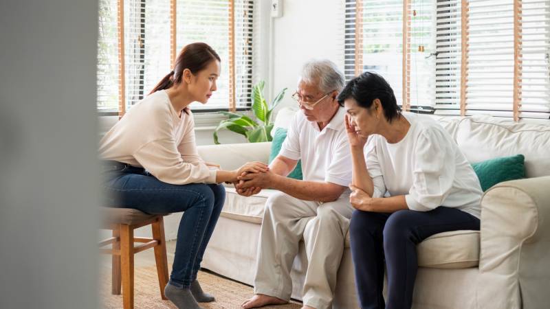 Three Asian people converse seriously (stock image)