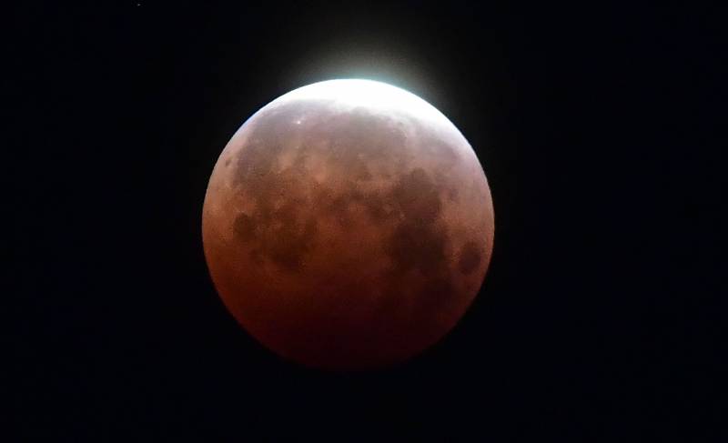 Red-orange full moon against a dark background
