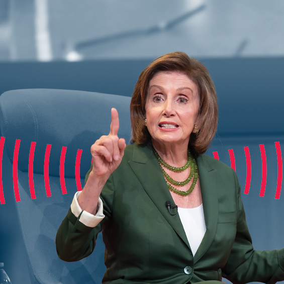 Speaker Nancy Pelosi wears a green jacket and looks at an audience.