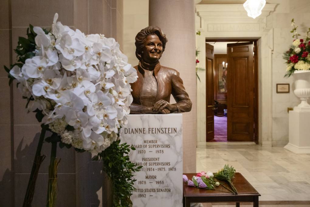 The bust of a person beside a large bouquet of flowers.