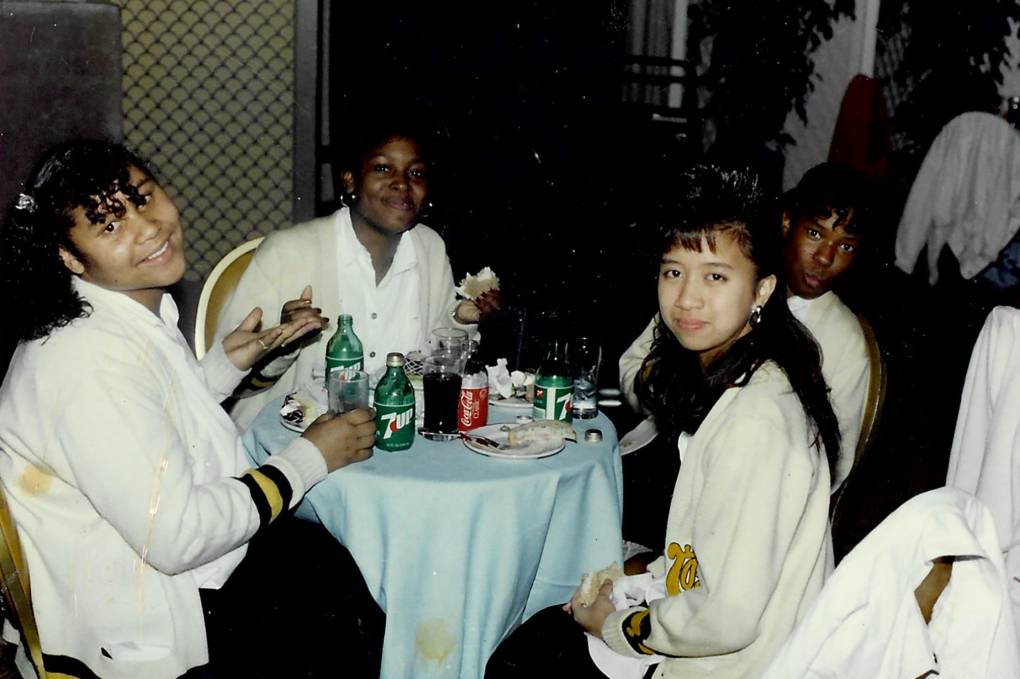 A group of young people sit at a table and smile at the camera.