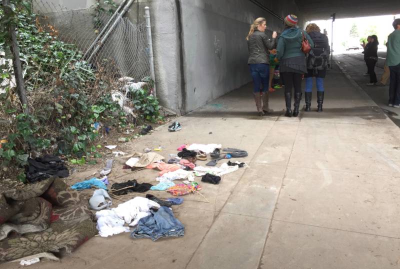 Trash and old clothes litter the sidewalk of an I-580 freeway underpass on West Street in Oakland