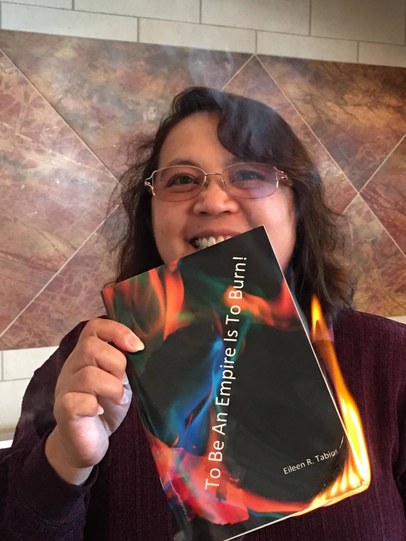Poet Eileen Tabios with her poetry chapbook 'To Be An Empire Is To Burn!' -- which she set on fire to reflect its title.