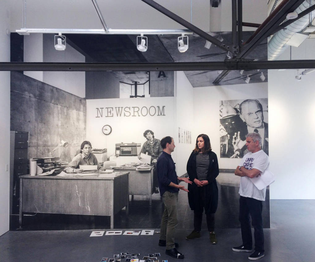 'Fake Newsroom' editors Jason Fulford, Dru Donovan and Jim Goldberg confer in front of an image of the 1983 installation 'Newsroom.'