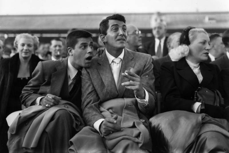 Dean Martin (center) sits with Lewis in 1953 at a boxing match.