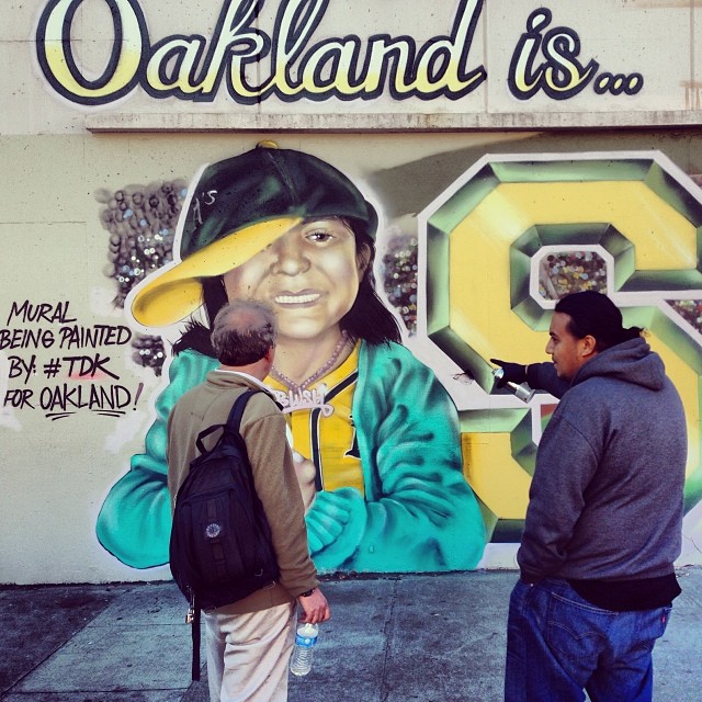 Amend shows a passerby his A's mural-in-progress in Jack London Square.