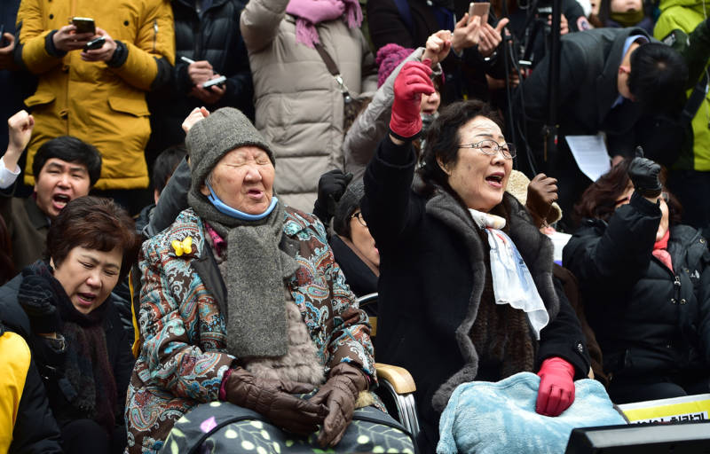 South Korean former "comfort women" Lee Yong-Soo (R) and Gil Won-Ok (C), who were forced into wartime sexual slavery for Japanese soldiers, shout slogans during an anti-Japanese rally commemorating the death of nine former sex slaves this year in front of the Japanese embassy in Seoul on December 30, 2015. South Korean "comfort women" and supporters vowed to step up protests against a deal between Seoul and Tokyo on resolving a long-running row over the comfort women. 