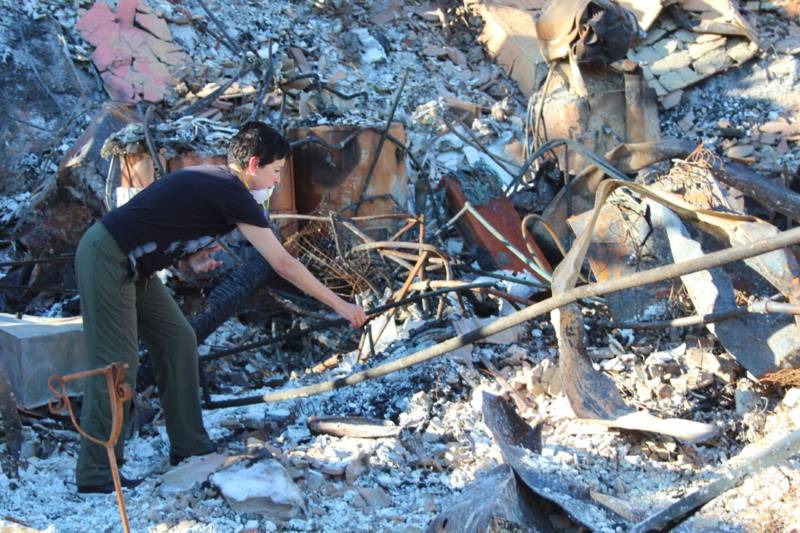 Norma Quintana searches for items in the ashes of her Napa home.