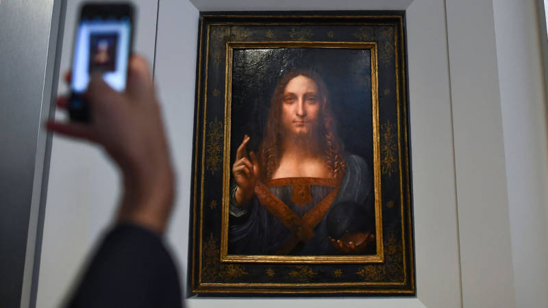 A journalist takes a photo of Leonardo da Vinci's "Salvator Mundi" after it was unveiled at Christie's in New York on October 10, 2017. One of fewer than twenty painting by Leonardo da Vinci and the only one in private hands, the Salvator Mundi sold for more than $450 million on Nov. 15, 2017, at Christie's New York.