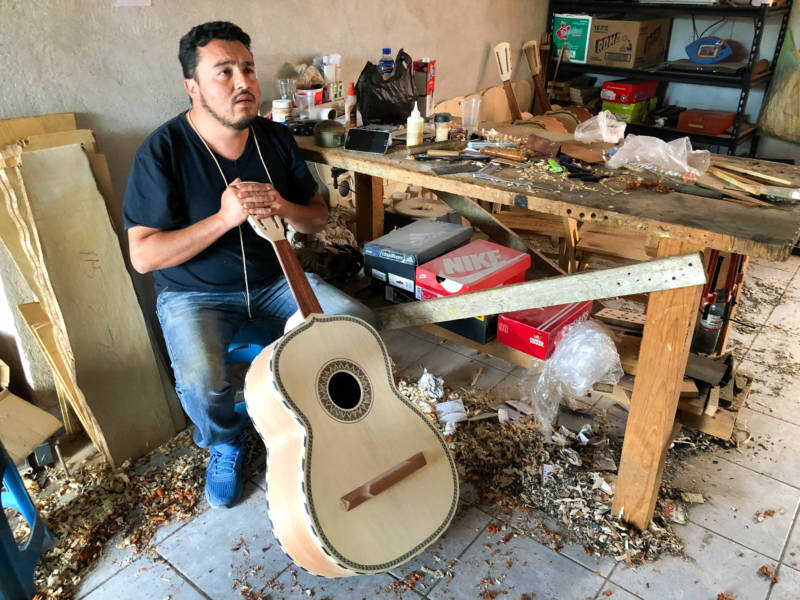 César Ivan Lemus, a third-generation Paracho artisan, shaves the neck of a <em>guitarrón</em> he’s making. Lemus sells all types of instruments to mariachi schools and stores in the U.S. He says he’s working as fast as he can to keep up with orders these