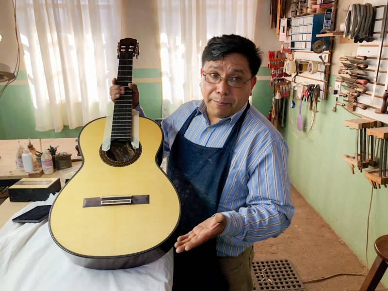 Master guitar maker Arnulfo Rubio Orozco holds up his latest project. It’s taken him a month to craft this guitar with pearl accents and wood from southern Mexico