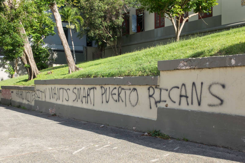 Grafitti on the steps of a high school in San Juan reads, “Harvard University wants smart Puerto Ricans.” Out-migration of Puerto Ricans, or “brain drain,” is a long-standing problem that has been accelerated in the wake of Hurricane María. Independent artists are especially vulnerable since shows and recording studios have been slow to recover.