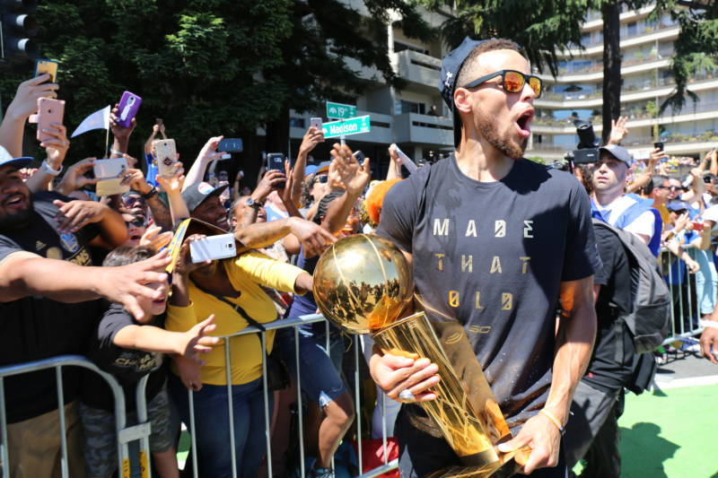Stephen Curry brings the NBA Championship trophy to the people during the Warriors parade in Oakland on June 15, 2017.