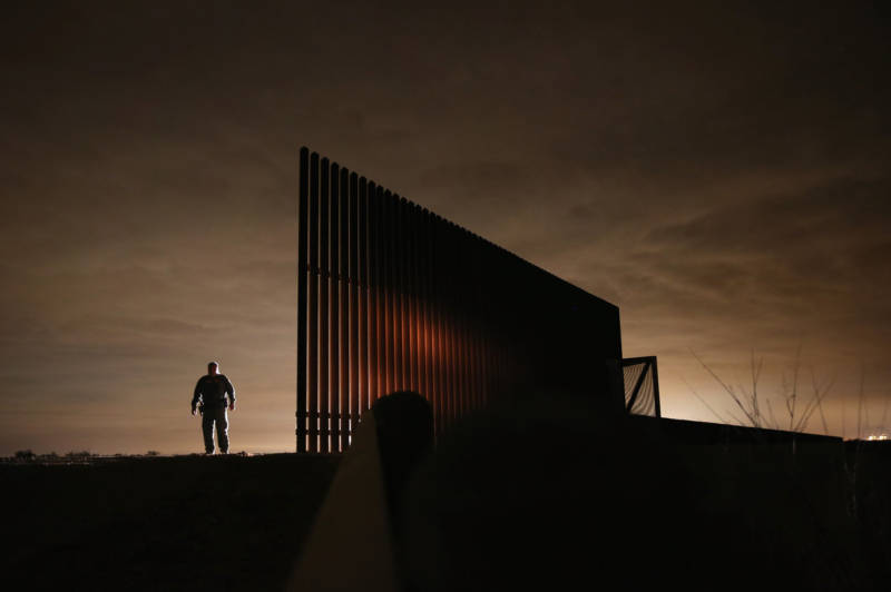 U.S. Border Patrol agent Sal De Leon stands near a section of the U.S.- Mexico border fence while stopping on patrol in 2013 in La Joya, Texas.