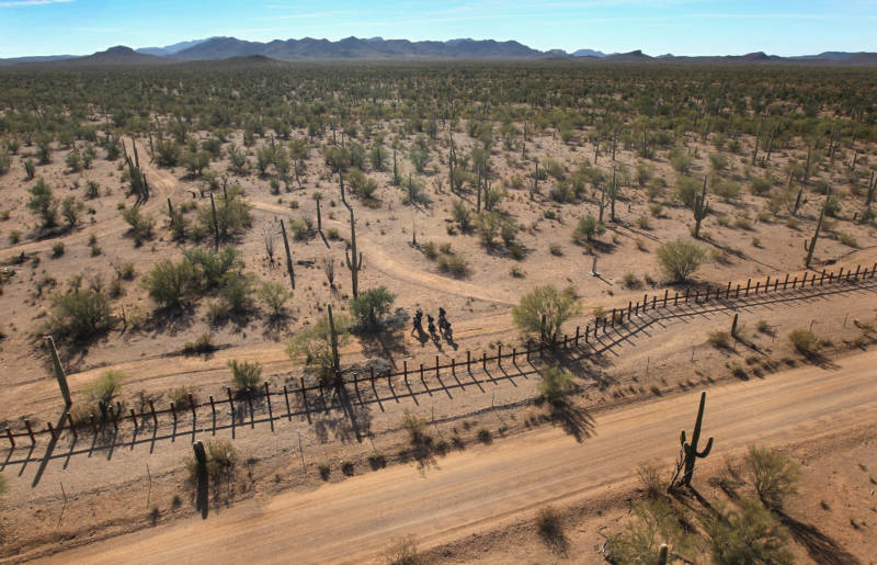 A group of young men walk along the Mexican side of the border fence in a remote area of the Sonoran Desert in 2010 on the Tohono O'odham Reservation in Arizona
