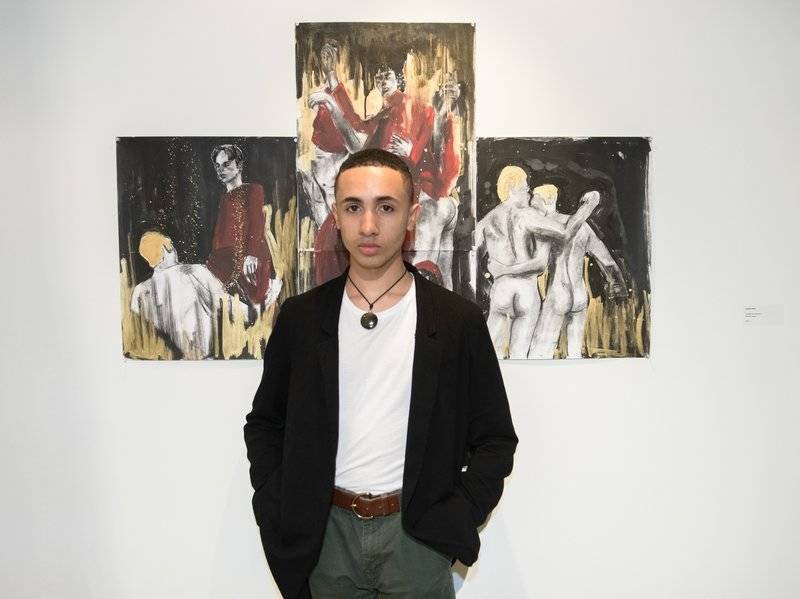 Juniel Solis poses in front of his work.