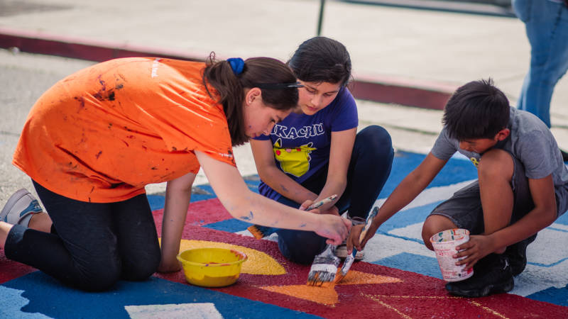Students help paint a mural near the ASCEND School in Oakland.