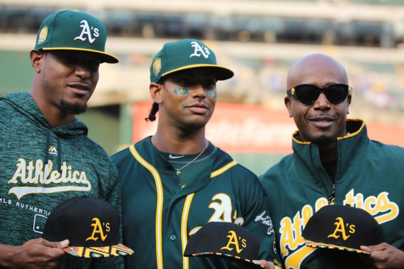 Edwin Jackson and Khris Davis show off their African American Heritage Night baseball caps with MC Hammer (L–R) at the Coliseum.