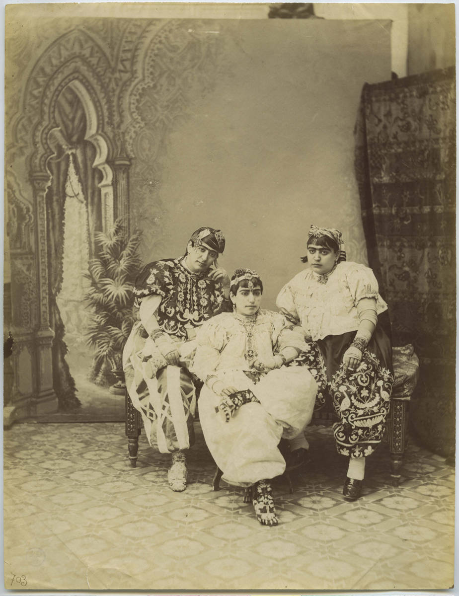 Three seated women in Tunisian trousers.