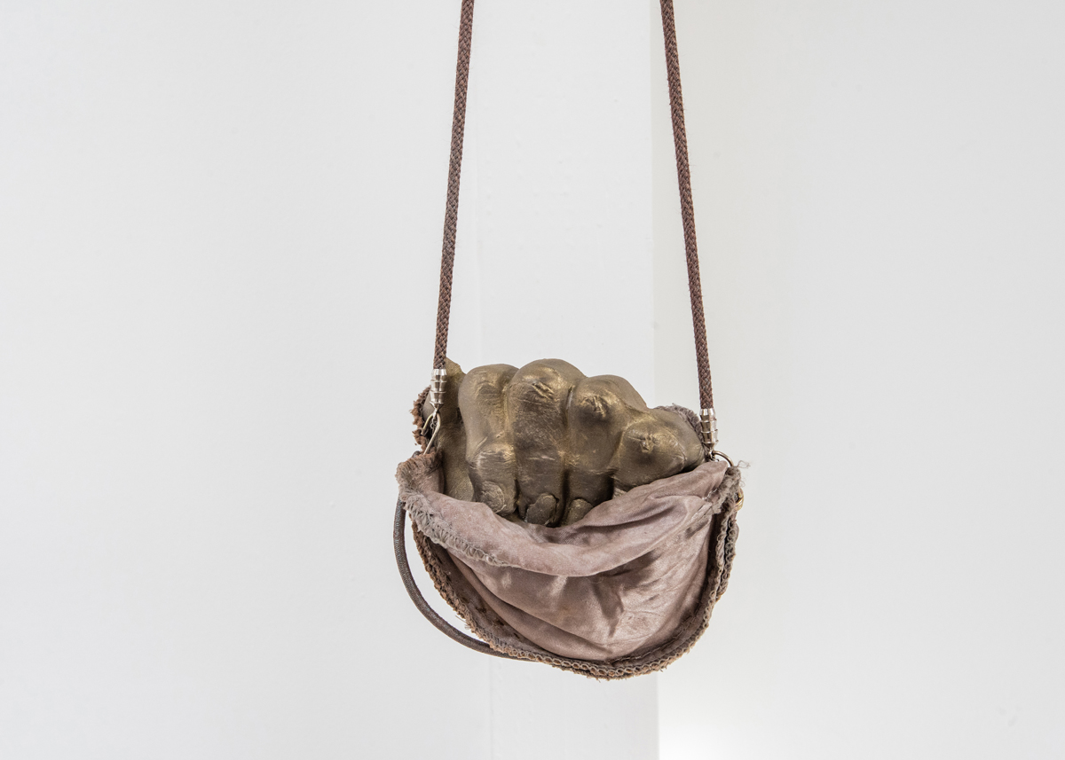 Jenine Marsh, 'fist in pocket' detail, 2018; Rust-stained shoulder-pads, necklace cord, bungee cord, staples, wire, powdered pigment, gypsum cement, steel hardware.
