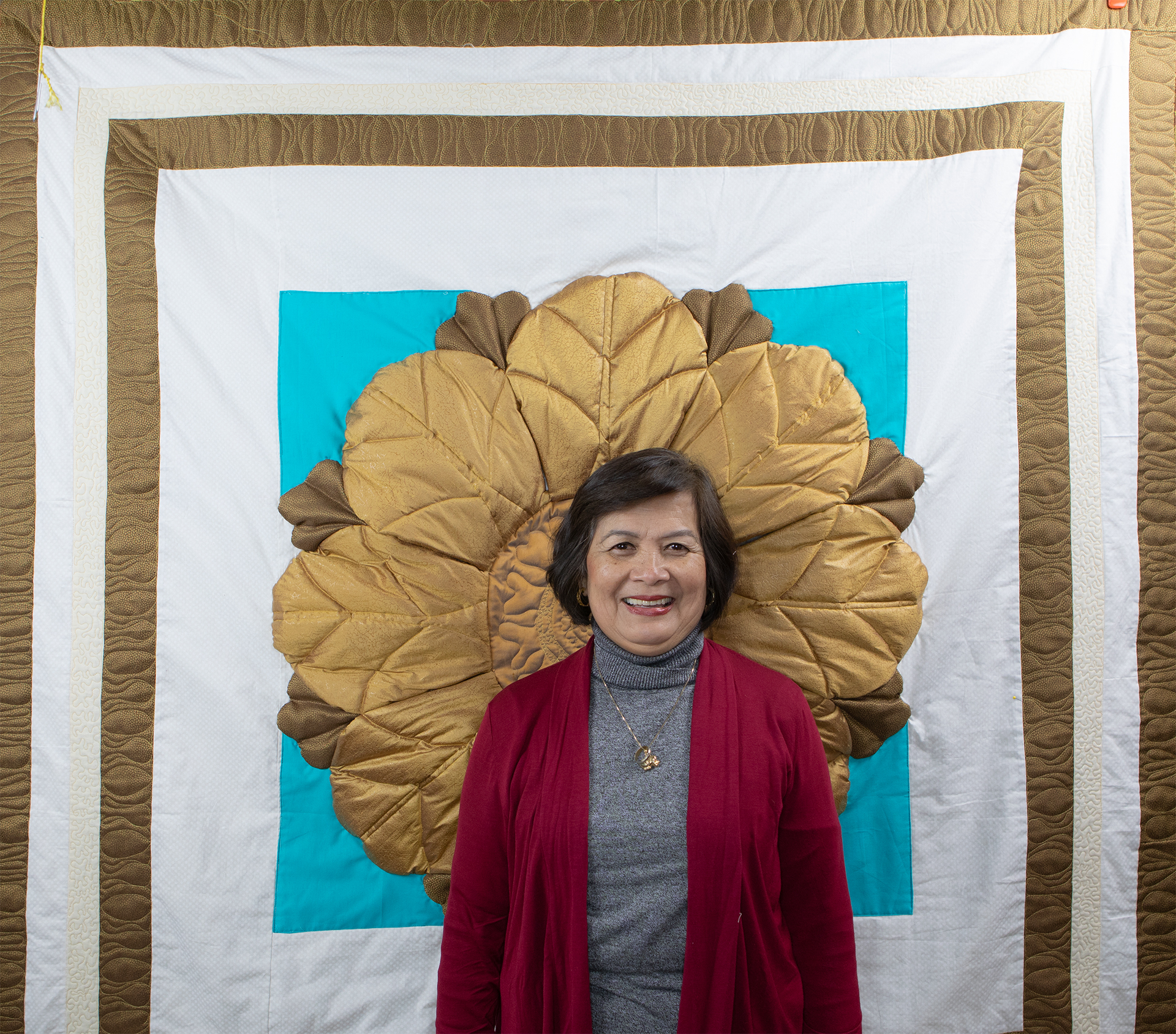 May Gaspay posing in front of a quilted version of a ceiling ornament from the Opera Building.