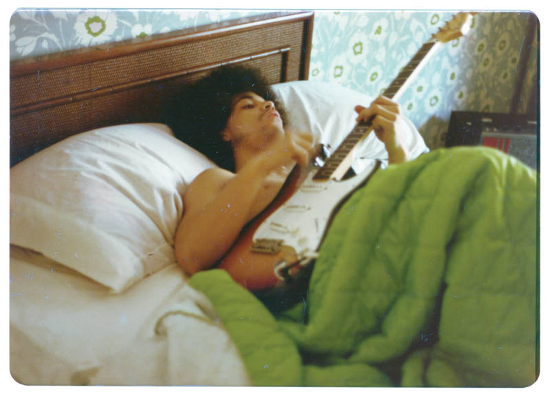 Prince plays a guitar in bed at his new home on France Avenue, April 1978.