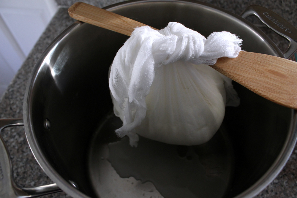 The curds then need to drain overnight wrapped in the muslin. I like to hang the sack of curds off of a spoon on top of a stockpot. Photo: Kate Williams