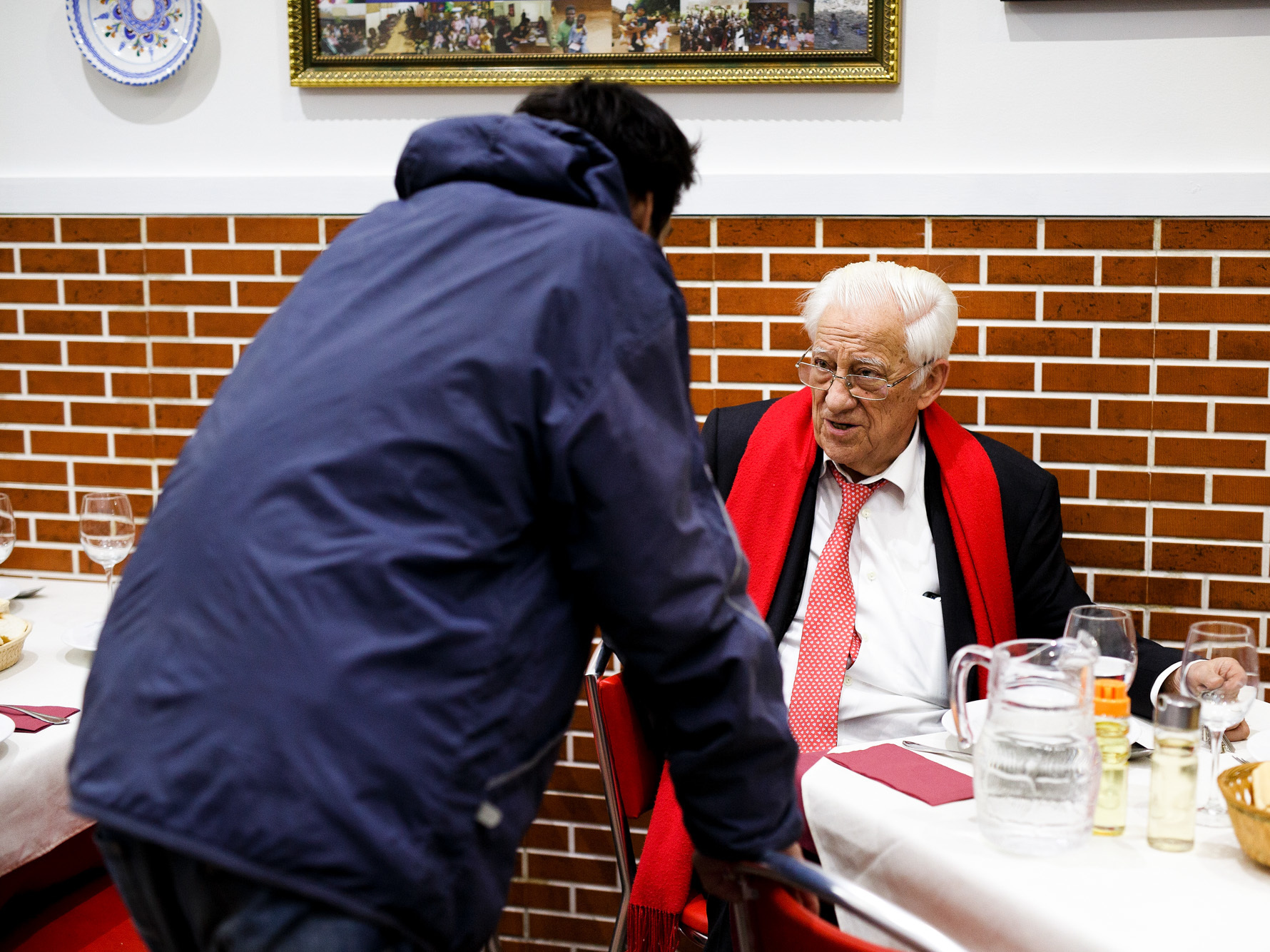 A dinner patron chats with Father Angel (right), who says that he wants homeless people to "eat with the same dignity as any other customer."
