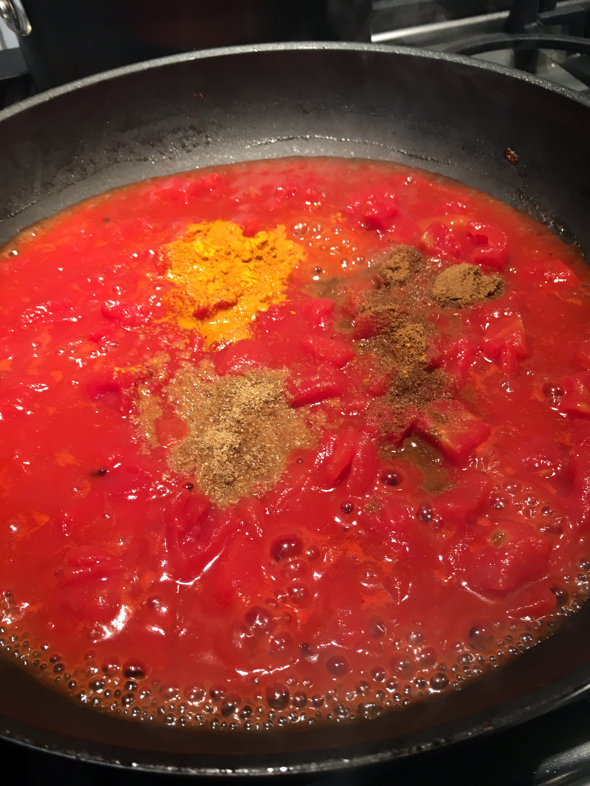 In the frying pan over medium heat, add the diced tomatoes. Cook until bubbling and warmed through, then add the cumin, coriander, turmeric, and the cayenne if using. Stir well, then let simmer for about 3 minutes until thickened. 