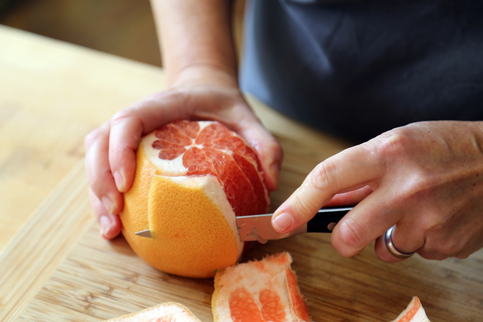 To segment the grapefruit, trim the top and bottom off of the grapefruit, then using a thin knife, cut away the peel and pith in sections, moving along the contour of the fruit.