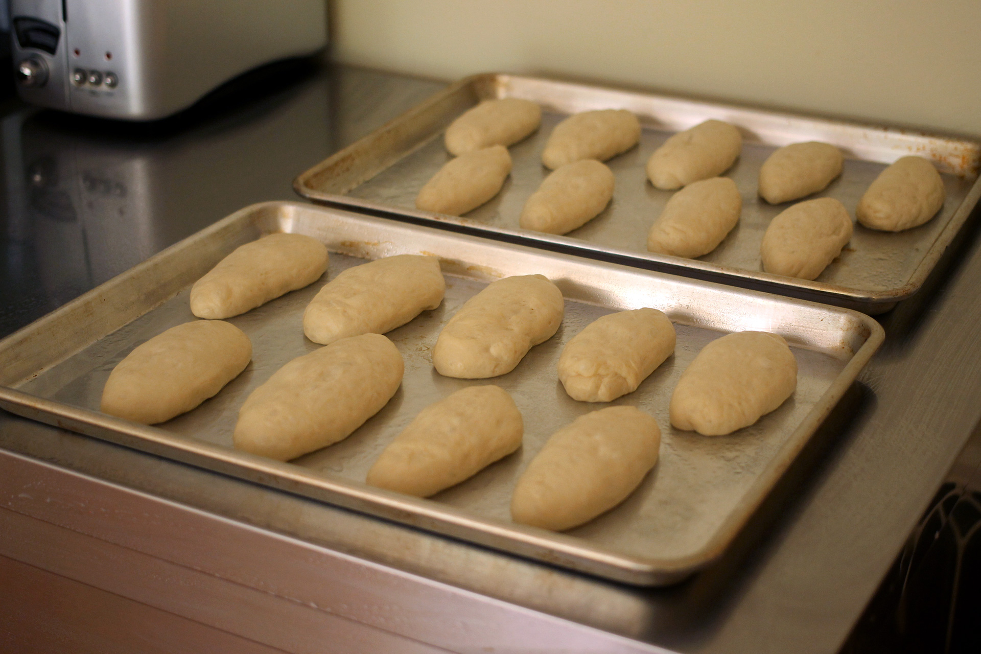 After rolling the balls into cylinders, place them on parchment-lined baking sheets — not greased sheets as you see above. (The buns will stick!)