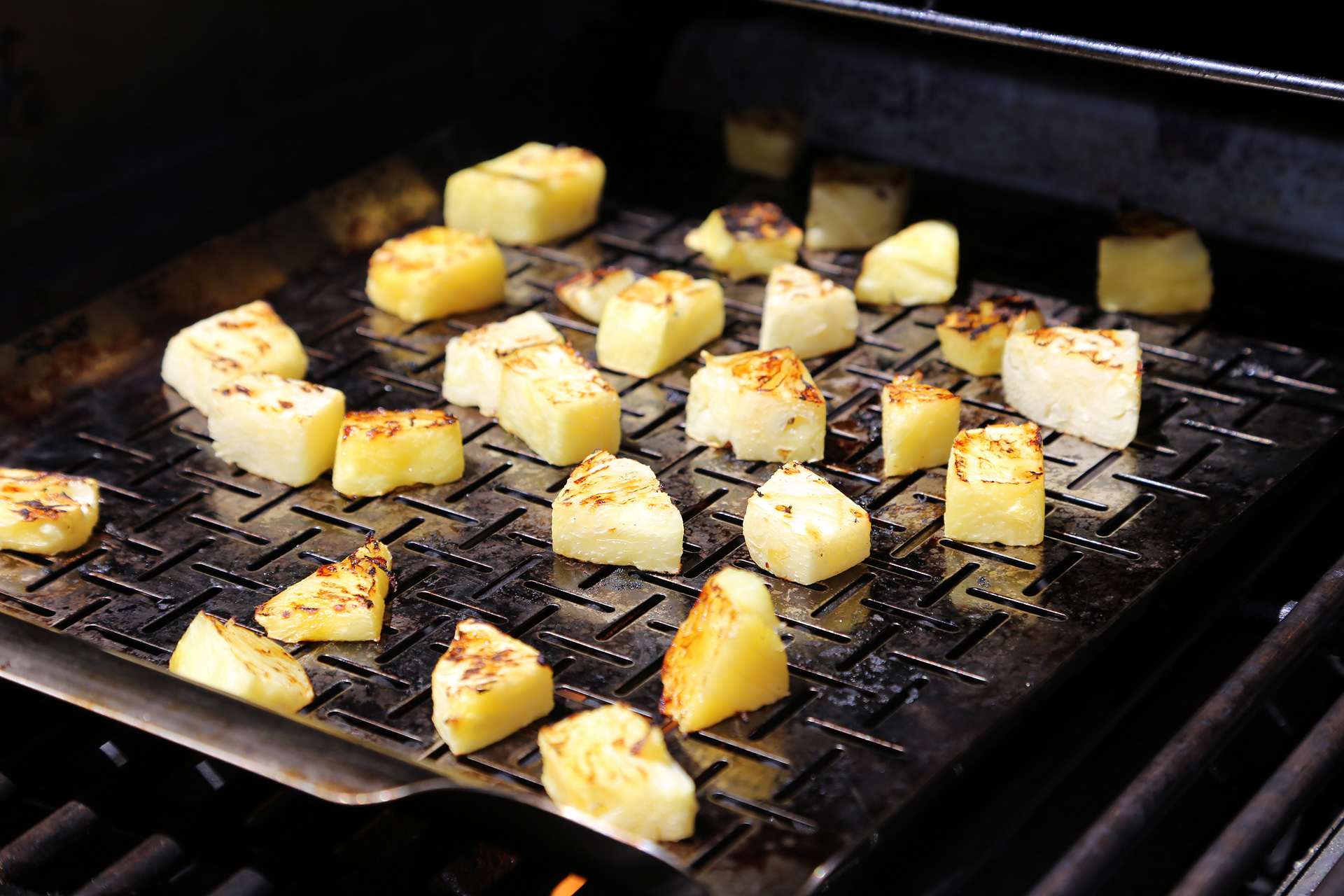 Using a perforated grill pan, grill the pineapple over direct heat until charred, about 7 minutes.