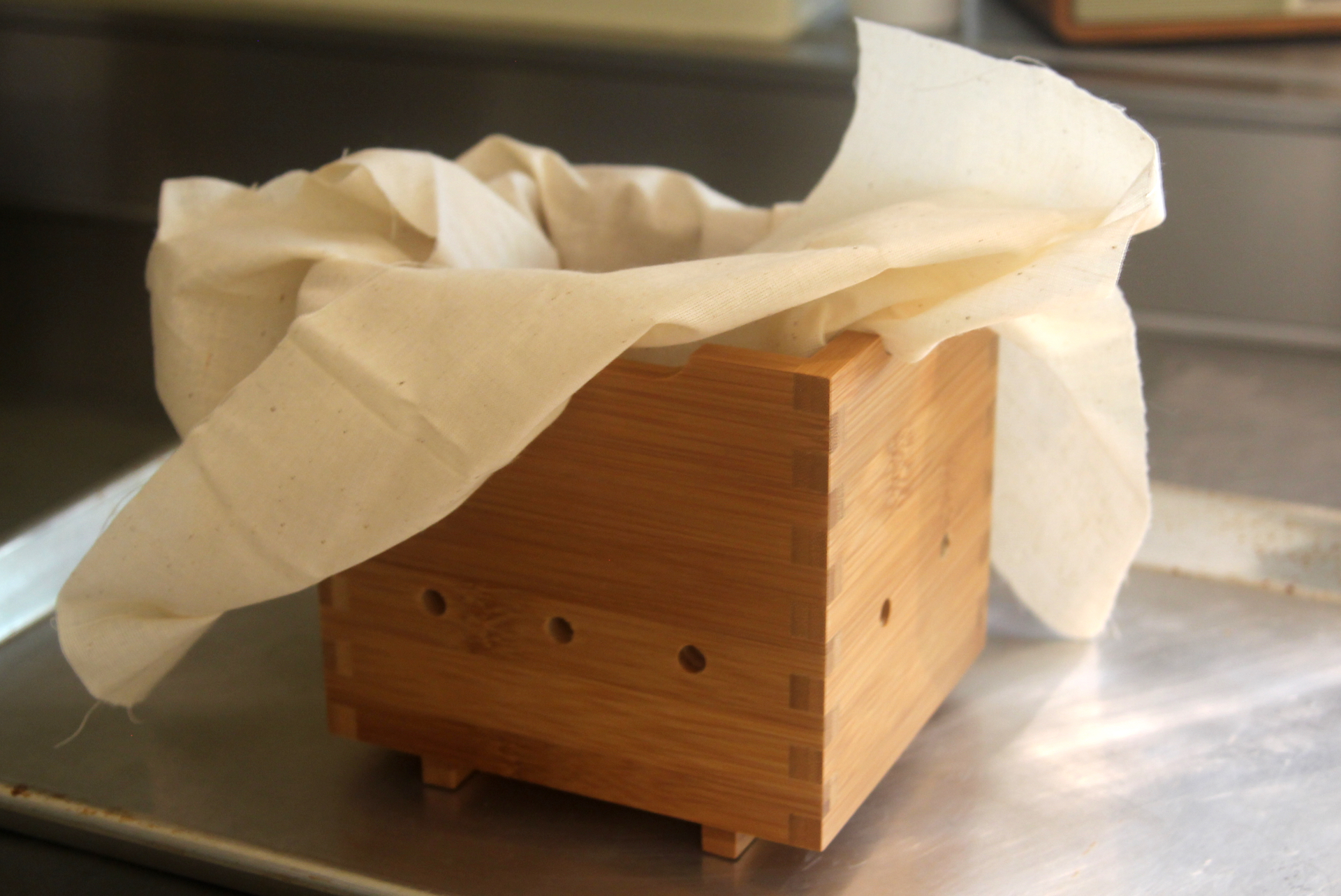 A wooden tofu mold with butter muslin.