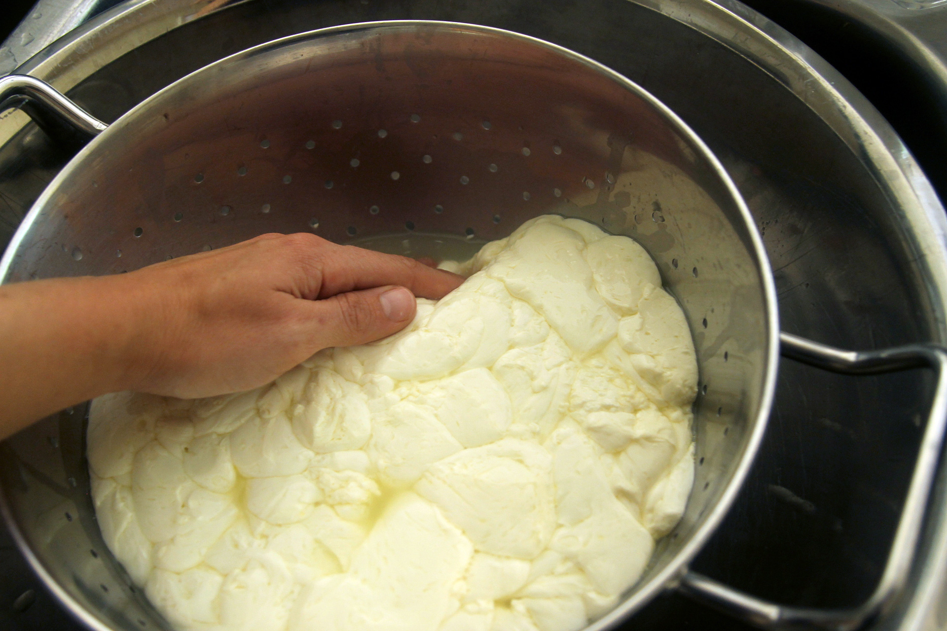 Gently press on the curds to encourage them to expel whey and form a solid mass.