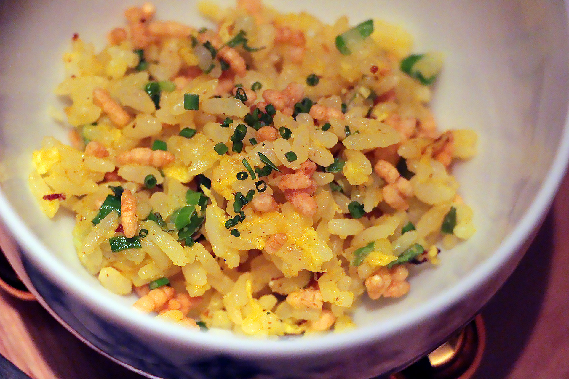 A bowl of fried rice with tiny pieces of egg and a crisped-rice garnish.