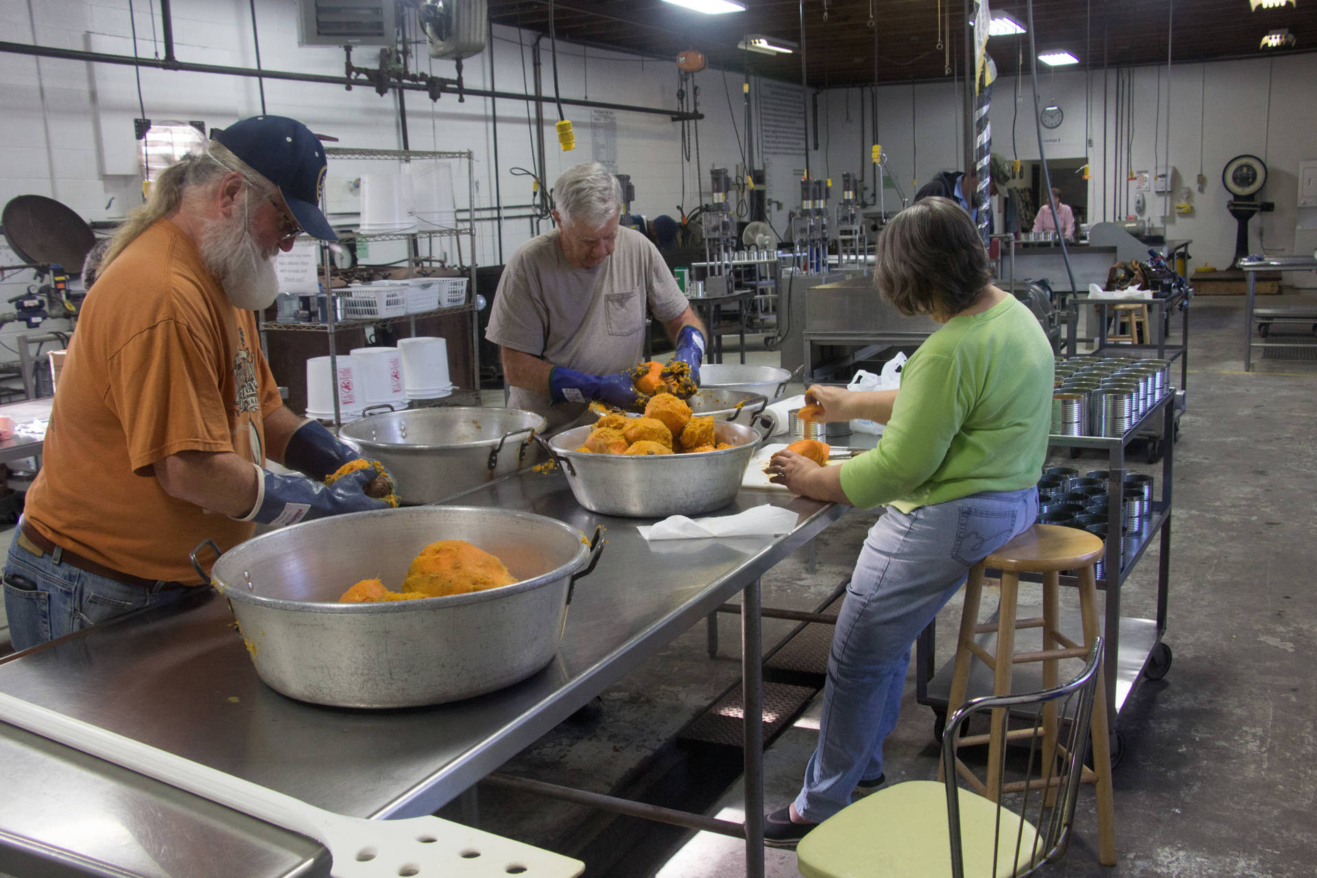 Tom Crouse (left), Lester Goin, and Becky Goin peel sweet potatoes in the Prince Edward County cannery.