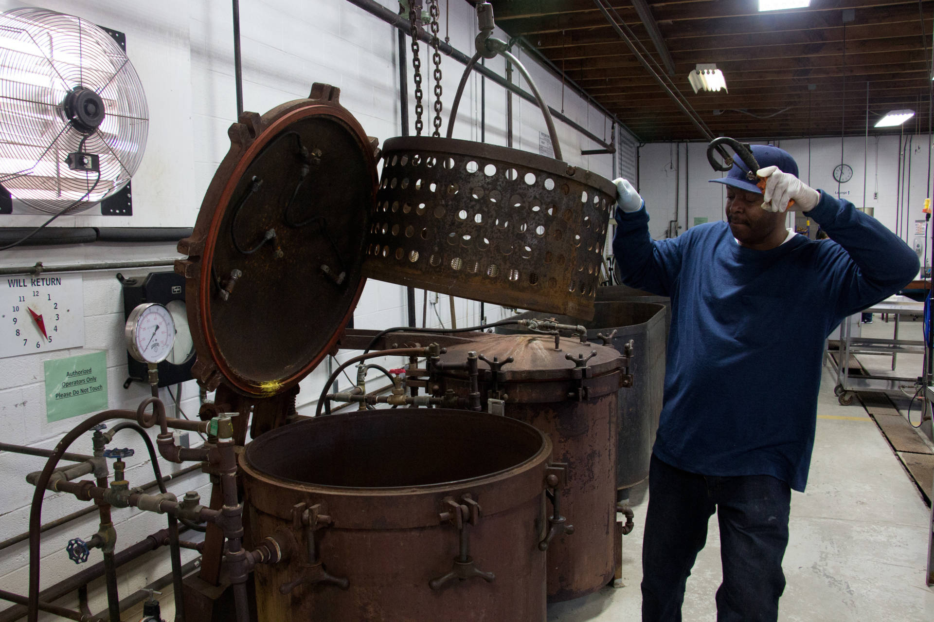 Rodney Scott, who works at the public cannery, loads a batch of cans into one of the two giant pressure cookers in the cannery.