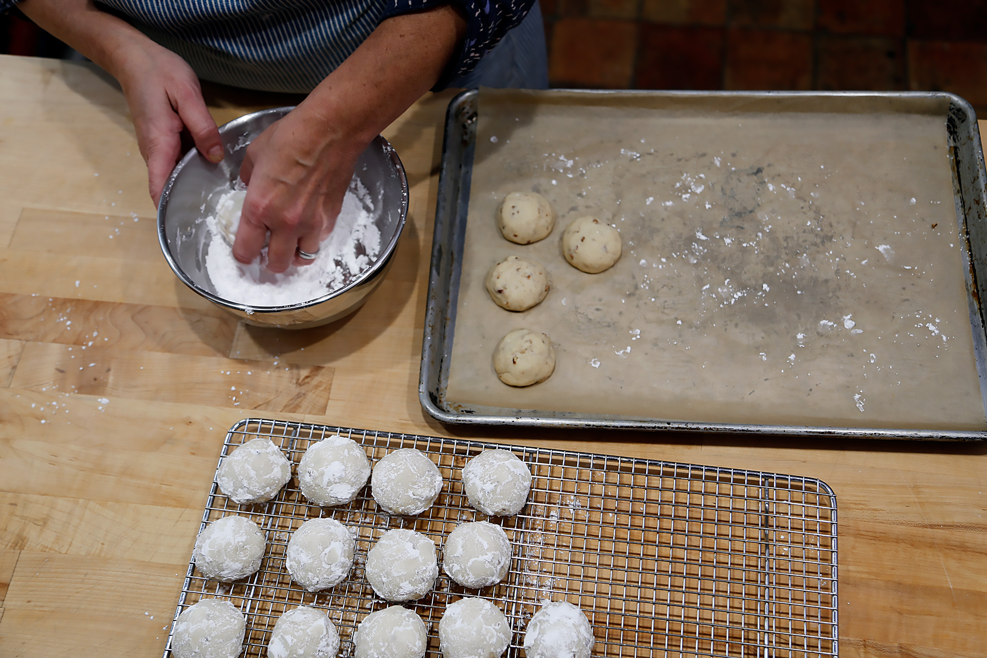 When cool enough to handle, roll the cookies in the reserved powdered sugar.