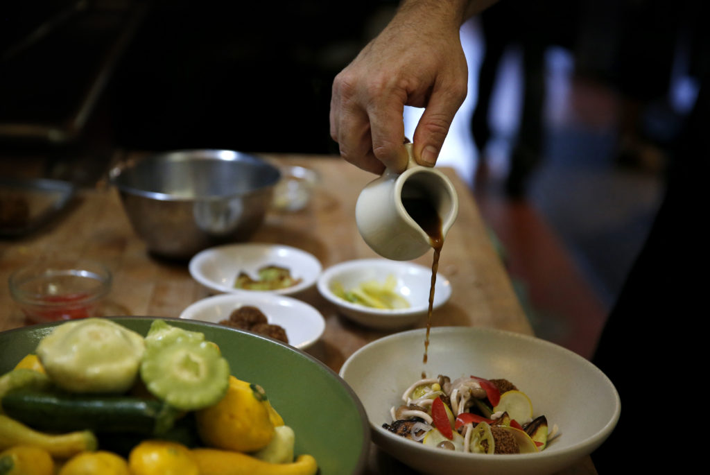 Chef Joe Zobel pours a a mushroom broth over a dish of squash "meatballs", squash crudo and pickled summer vegetables at Peter Lowell's Restaurant in Sebastopol.