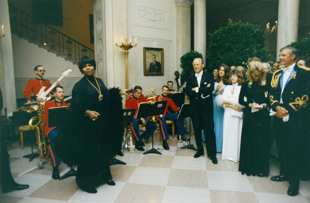 President Ford watches Pearl Bailey perform in the White House Entrance Hall during a state dinner in May 1975.