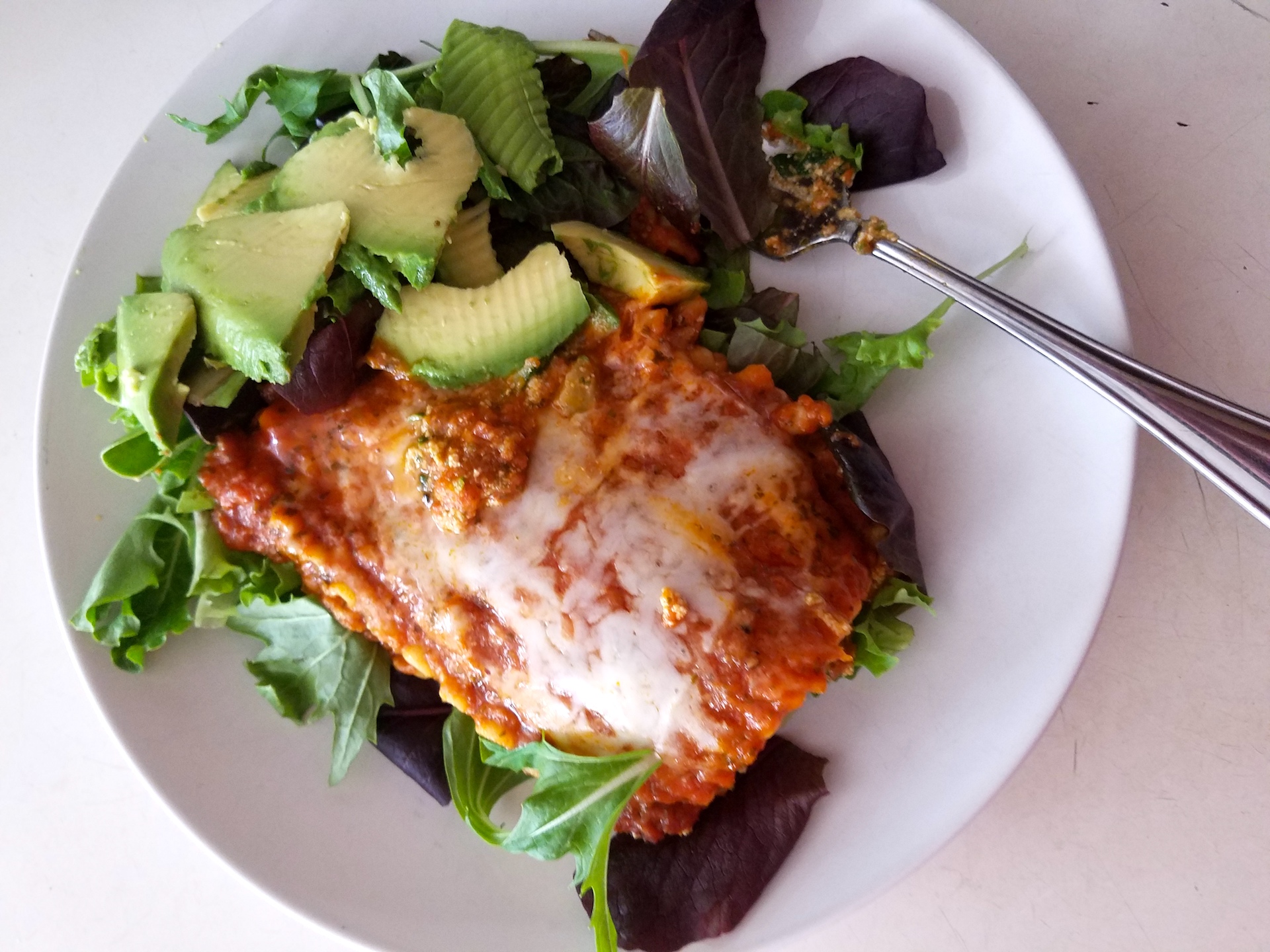 Amy's veggie lasagna on a bed of lettuce with avocado.