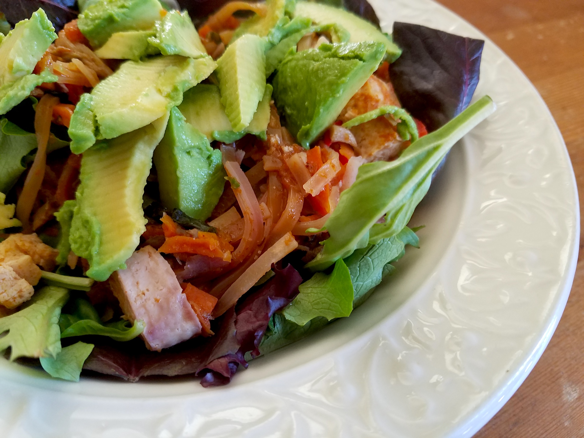 Pad thai in a lettuce bowl with avocado.