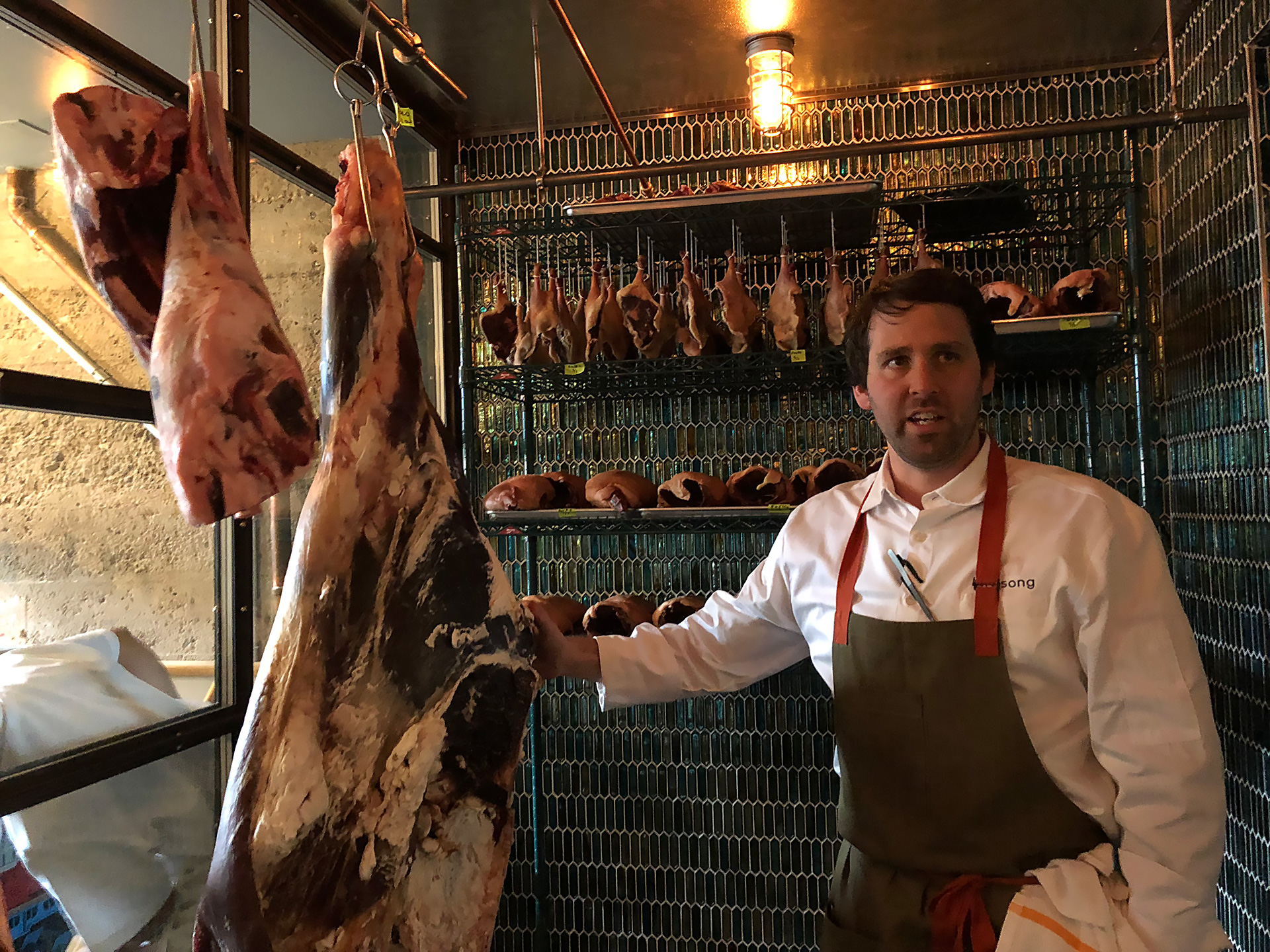 Chef Chris Bleidorn talks about the various cuts of meat in the glassed-in meat cooler.