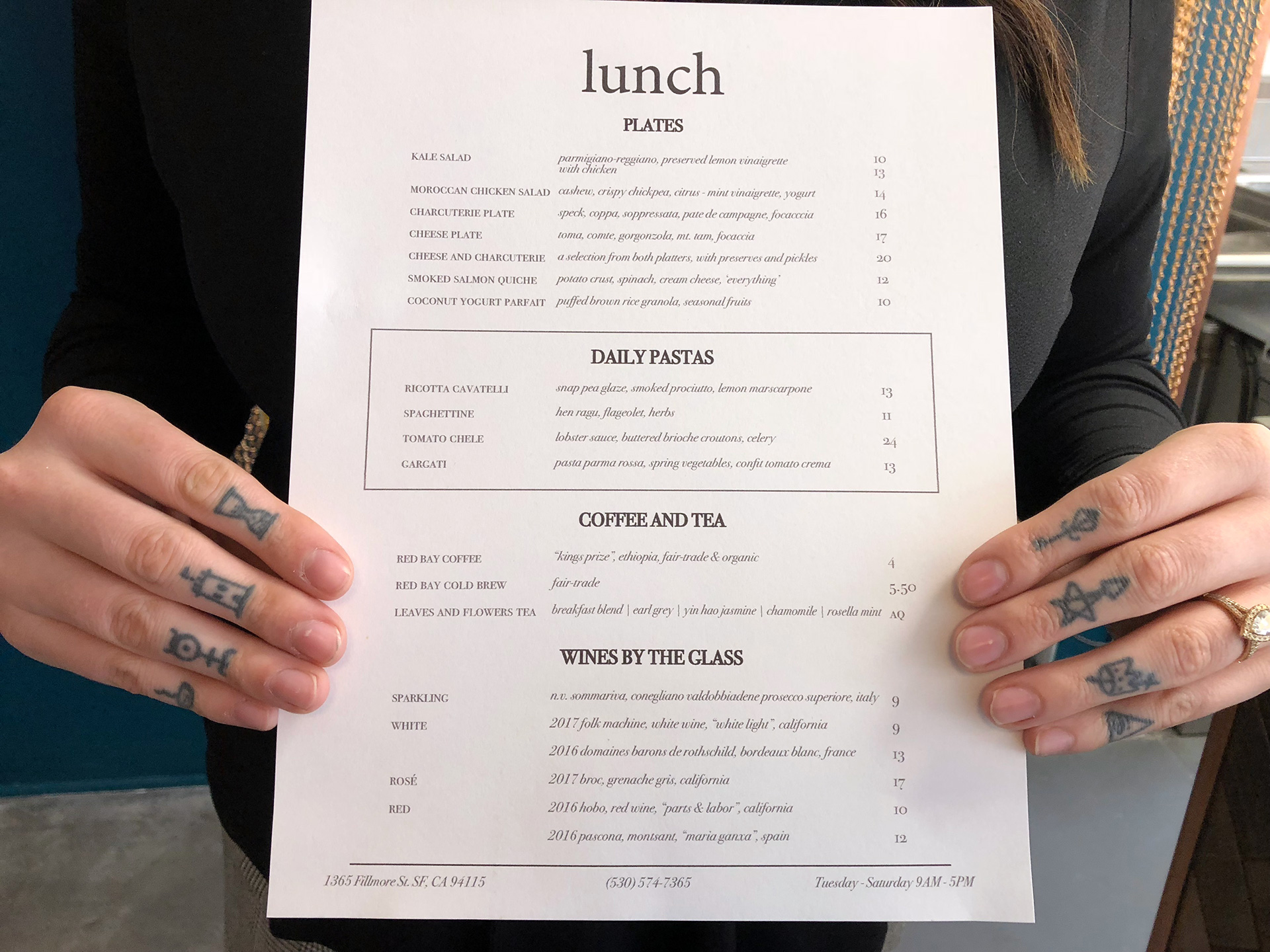 Madison Michael's hands showcase the lunch menu at Merchant Roots