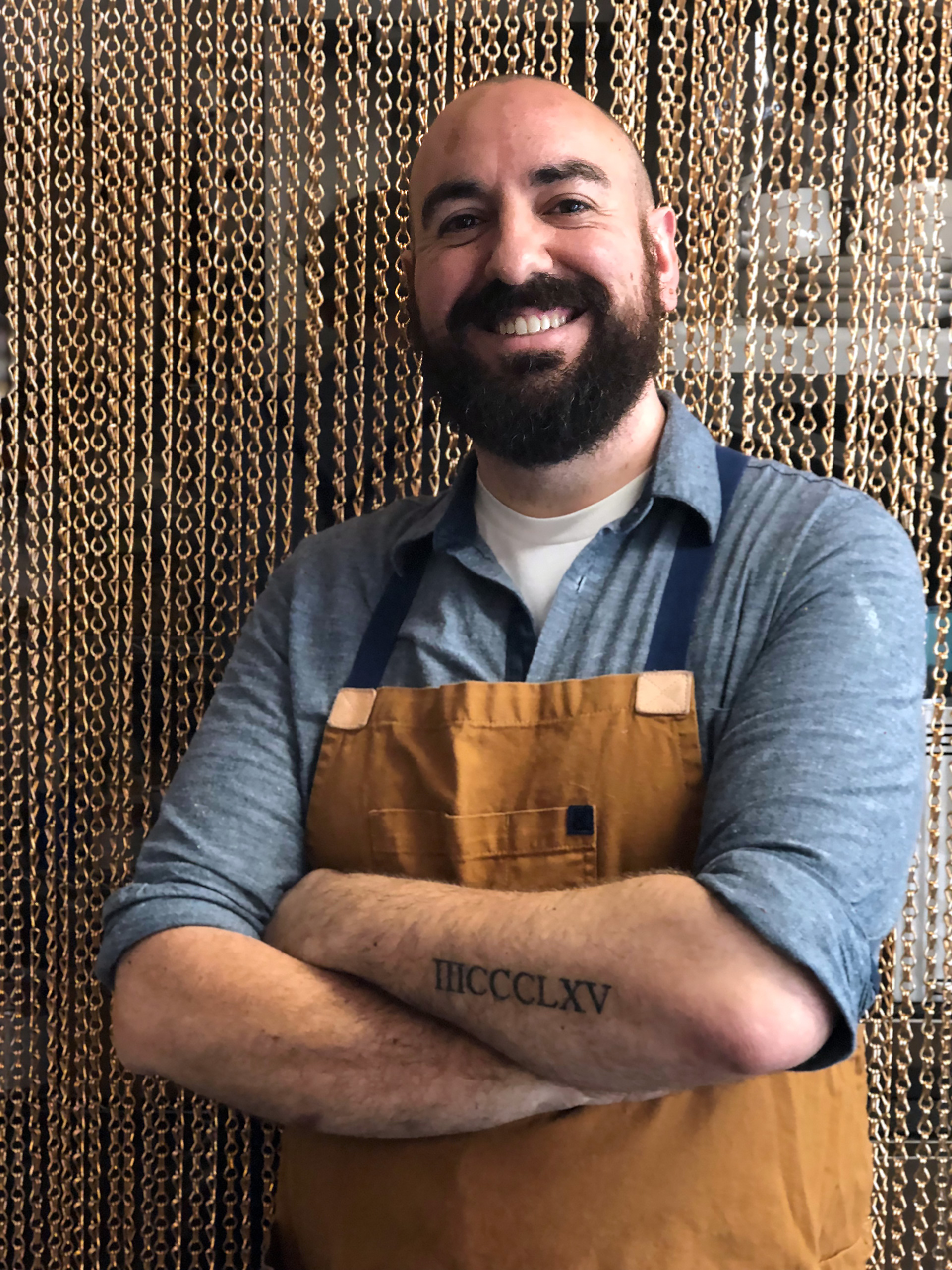 Executive Chef/Proprietor Ryan Shelton shows his recently acquired tattoo that is the address of Merchant Roots in Roman numerals.