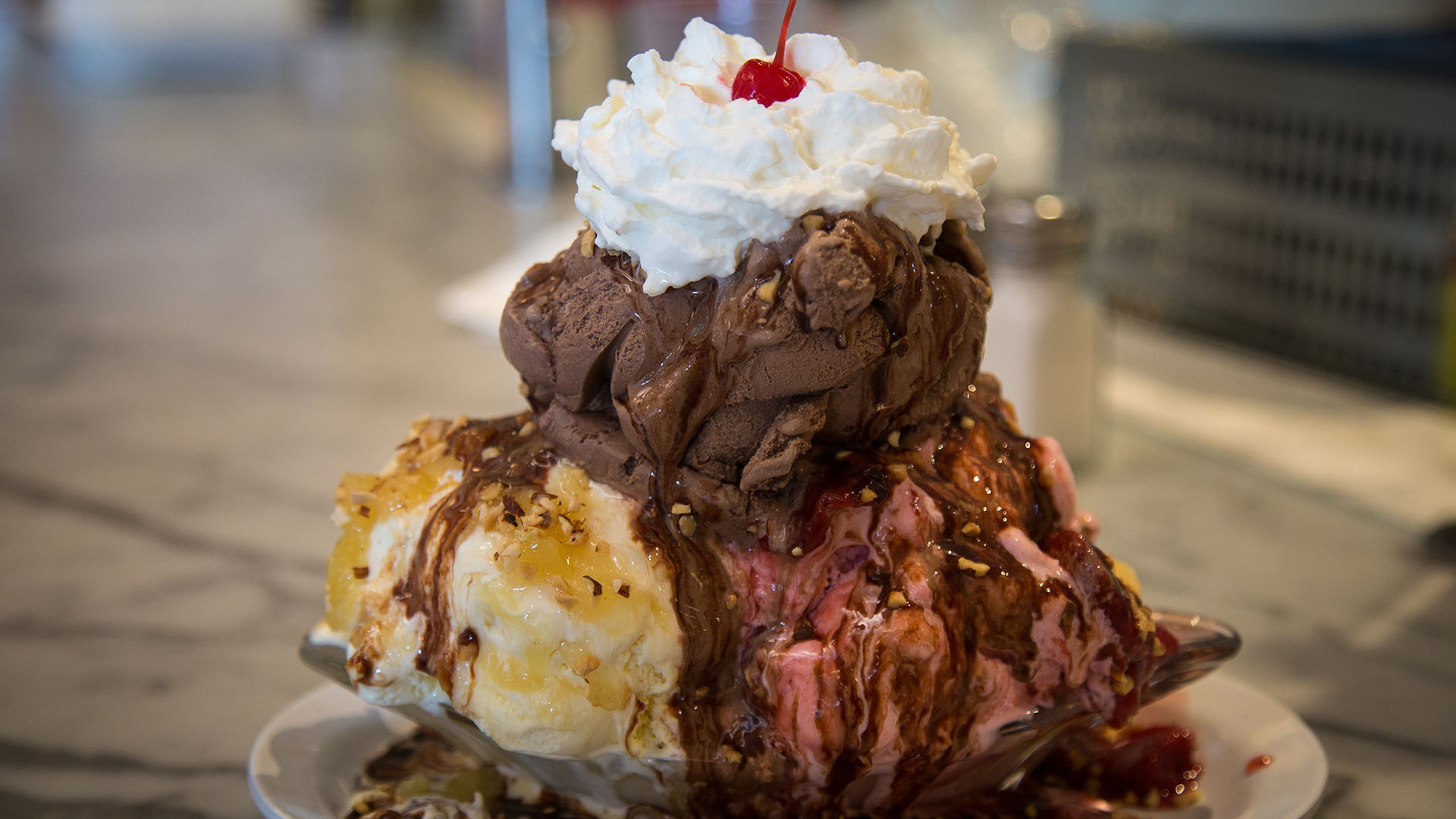 The Banana Special, a ripe banana, giant scoops of chocolate, strawberry, and vanilla ice creams with chocolate, strawberry, and pineapple sauce and whipped cream, almonds, and topped with a cherry. 