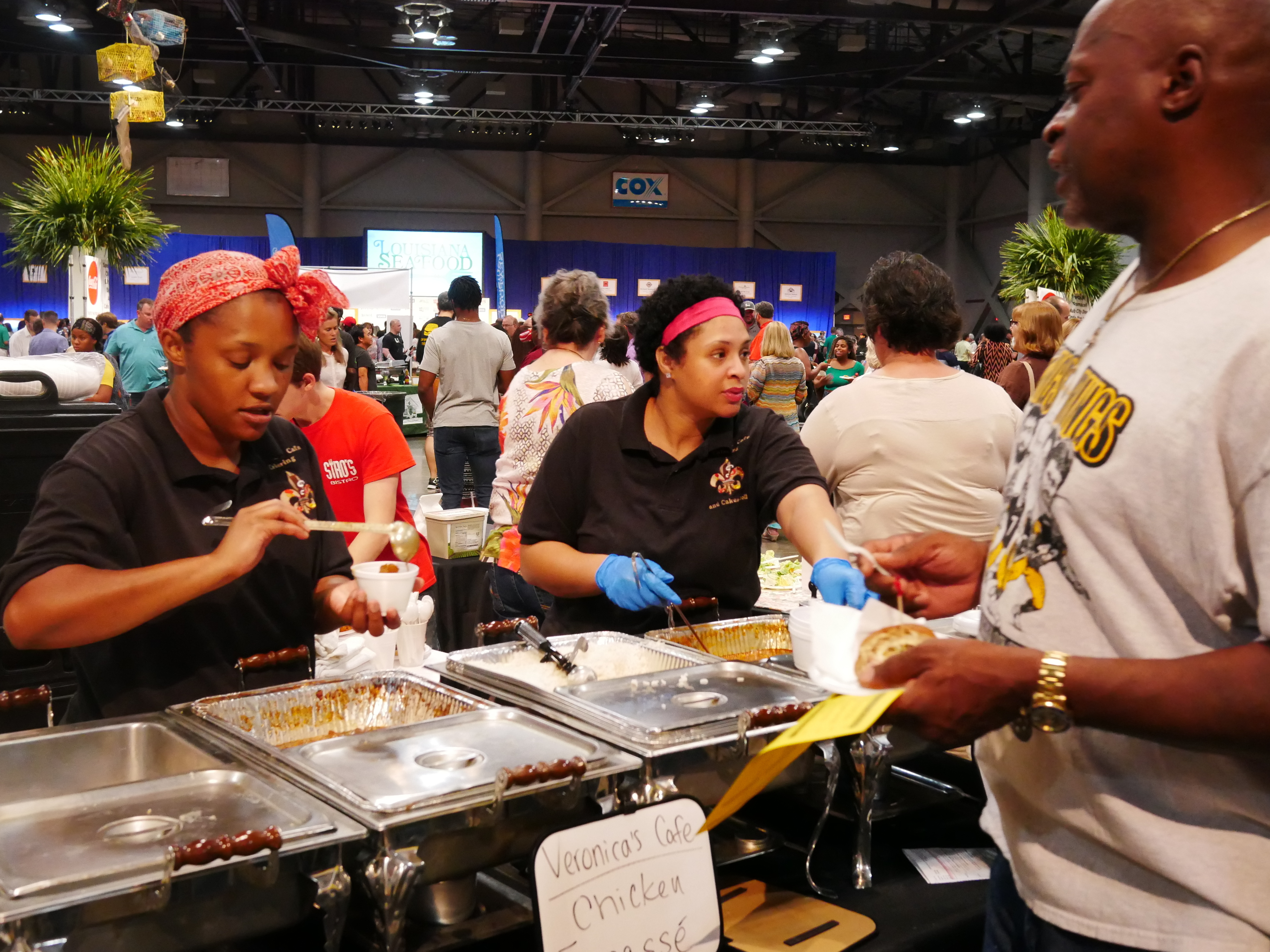 Restaurant workers dole out chicken fricassee at the "Taste of EatLafayette" festival in the sprawling Cajundome arena in Lafayette, Louisiana. Locals say Bourdain captured the subtleties of their culture and cuisine, even if at times some thought he overemphasized alcohol.