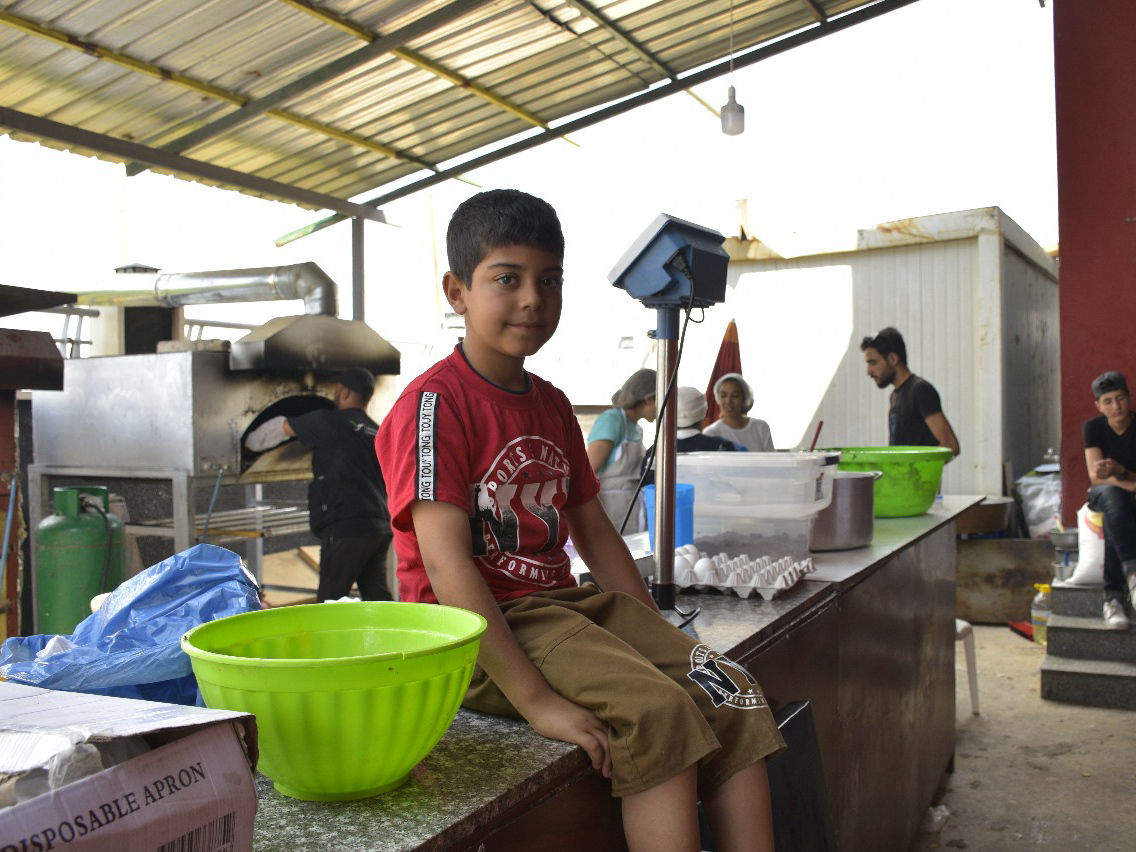 Bashar, sits on a table for prepping meals in the Ramadan Kitchen.
